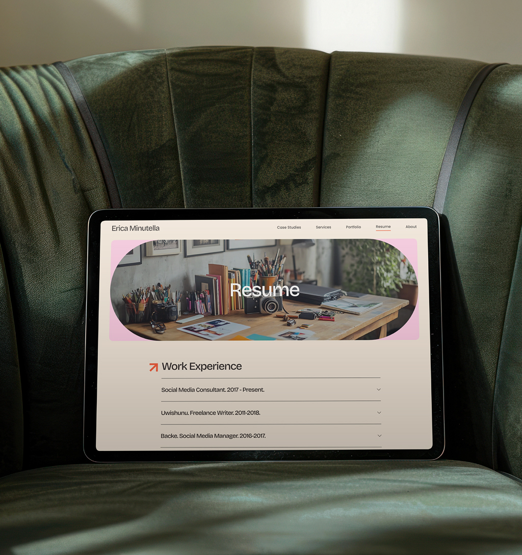 EricaMinutella-Resume Tablet displaying the resume page from the Erica Minutella website rests on a green velvet chair. The screen shows work experience with a creative desk setup in the header.