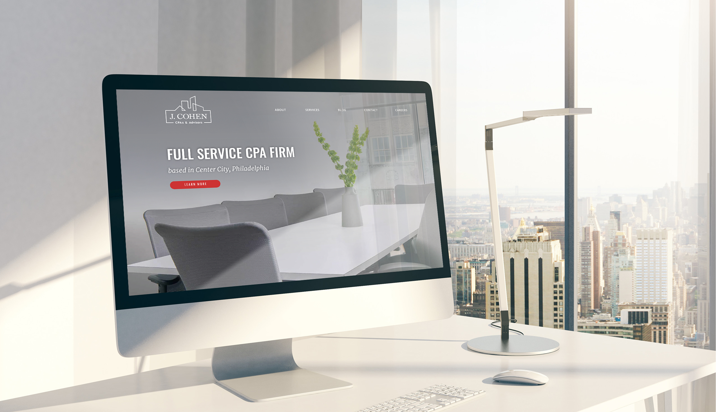 Modern office with a city view, featuring a computer displaying the J. Cohen website. Sunlit, sleek desk with a lamp, creating a professional ambiance.