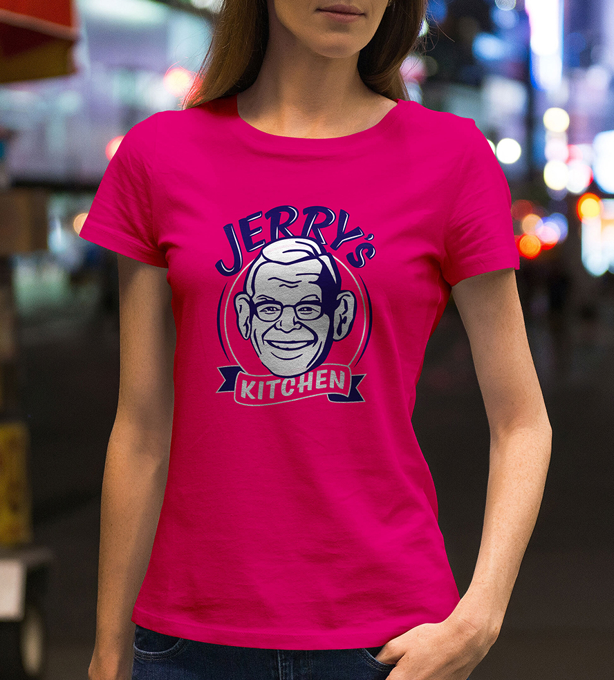 JerrysKitchen-Shirt Woman wearing a bright pink t-shirt with a cartoon-style logo of a smiling older man and the text "Jerry's Kitchen" in a busy nighttime city scene.
