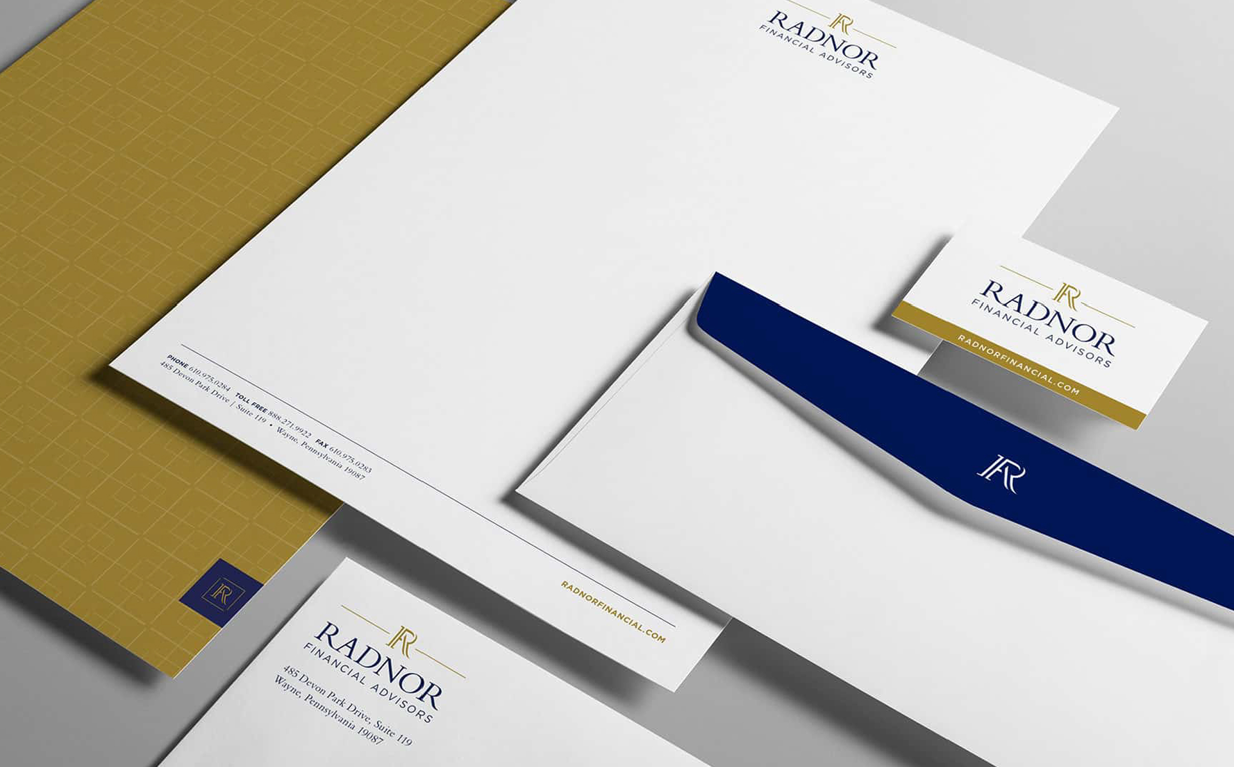 Stationery set for Radnor Financial Advisors featuring letterhead, business card, envelope, and folder in white, gold, and navy, displaying elegance and professionalism.