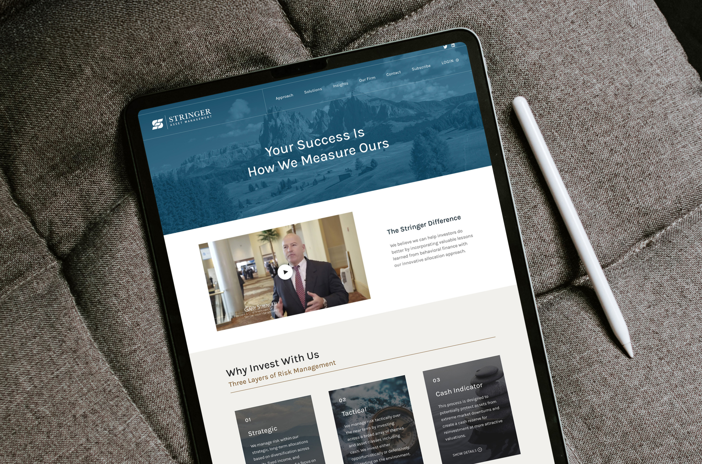 Tablet on a cushion displaying the Stringer Asset Management website with a stylus beside it.