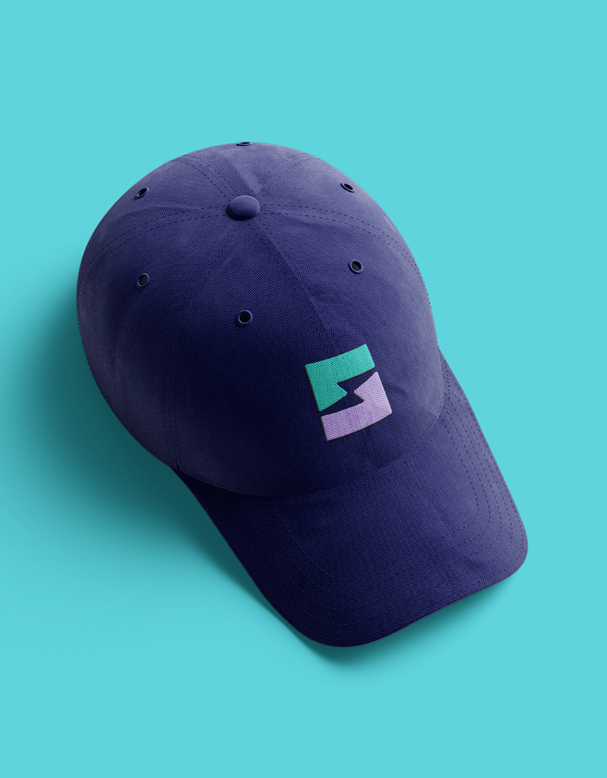 A navy blue baseball cap on a turquoise background with a geometric logo featuring teal and purple shapes on the front, conveying a modern vibe.