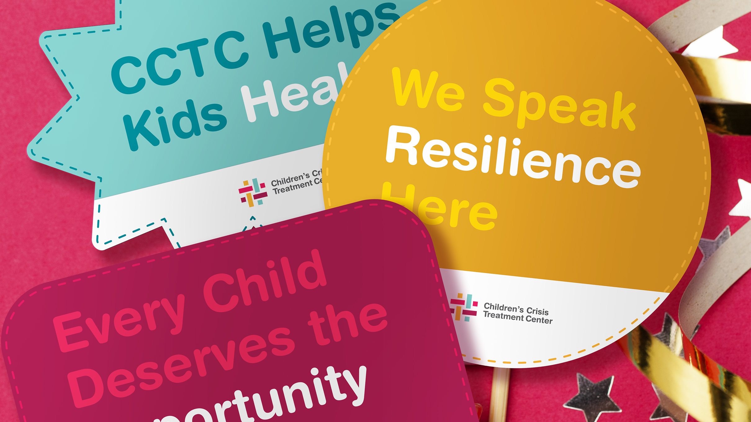 Colorful signs on a pink background. One reads, "CCTC Helps Kids Heal," another says, "We Speak Resilience Here," and the last one says, "Every Child Deserves the Opportunity."