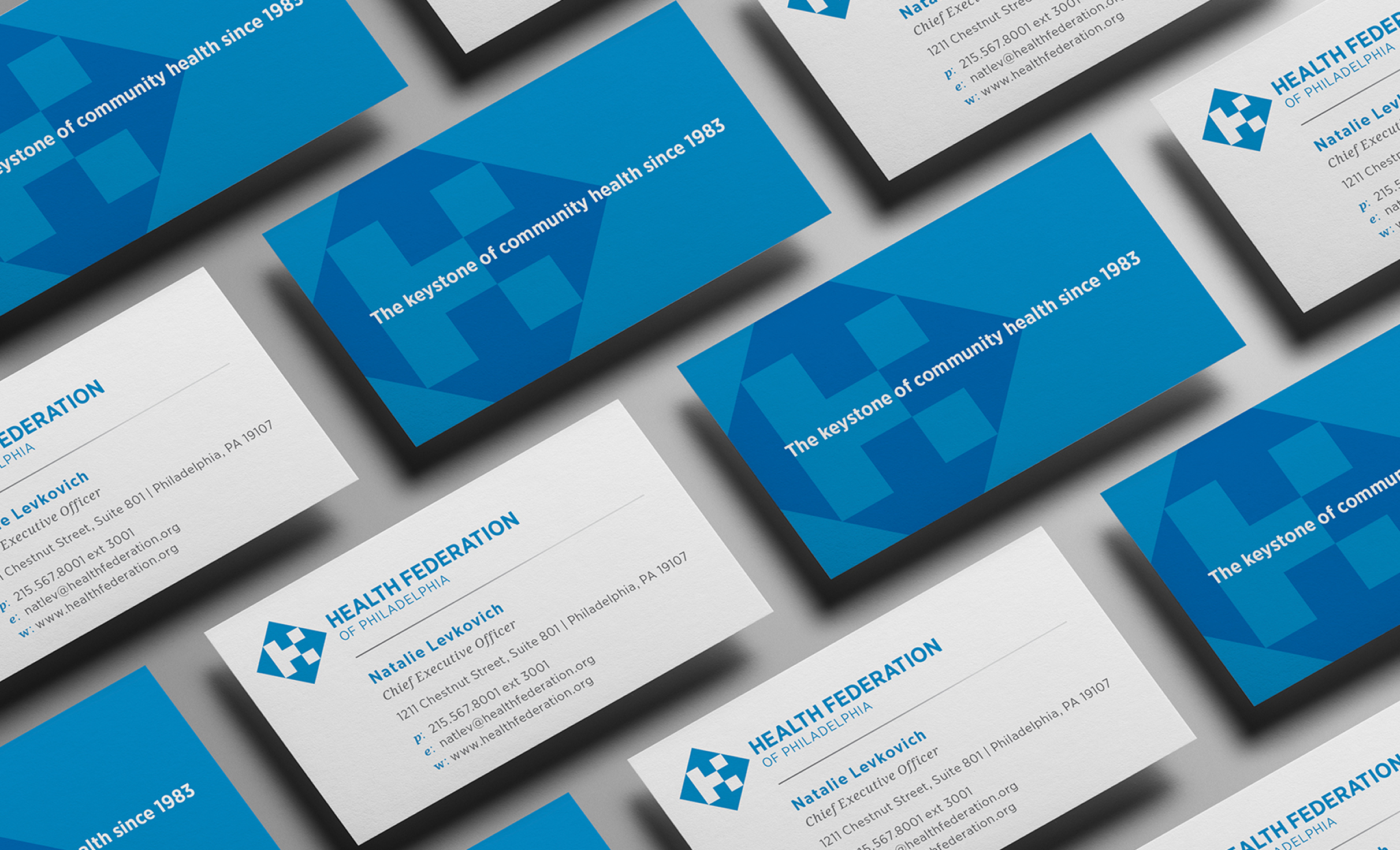 HealthFed-BusinessCards A set of blue and white business cards with the Health Federation logo are neatly arranged. Cards display contact information.