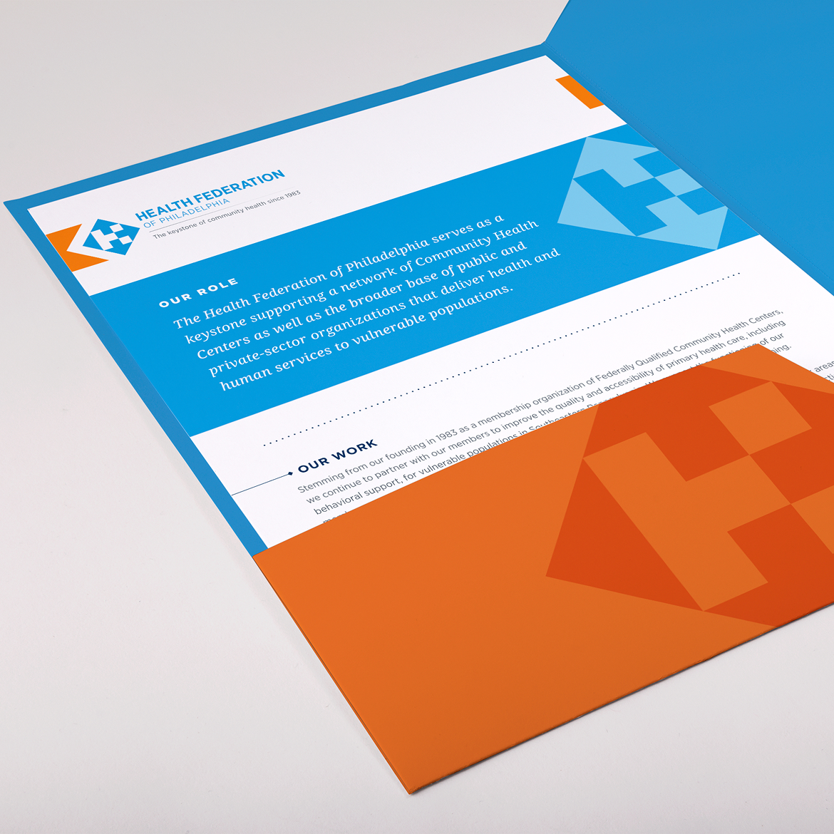 HealthFed-Folder An open brochure features blue and orange sections with text about the Health Federation of Philadelphia. The design includes a geometric "H" logo.
