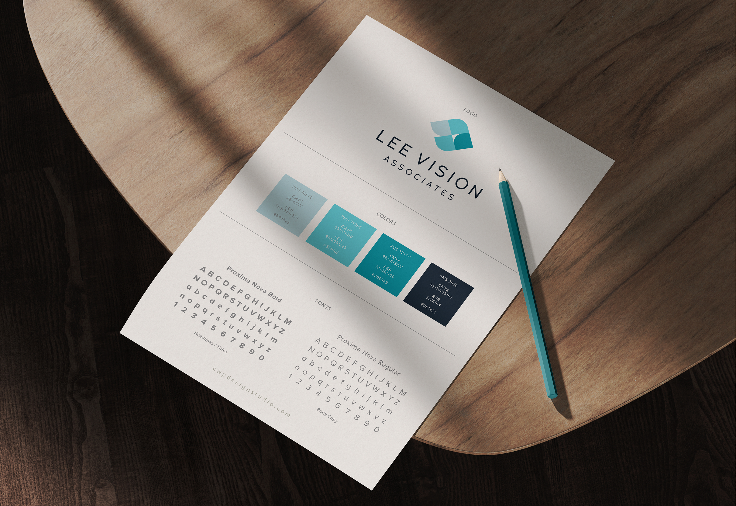A style guide on a wooden table shows the logo "Lee Vision Associates," color palette with blue hues, and font styles. A pencil lies beside it.