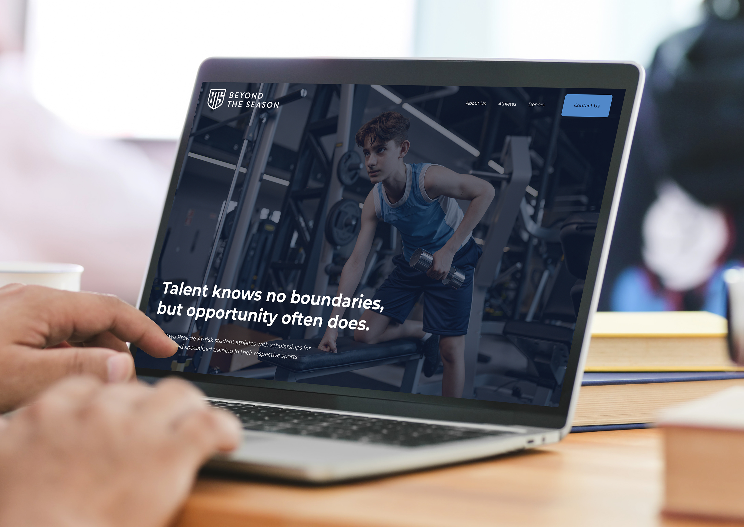 A laptop screen displaying the homepage for Beyond The Season. Pictured is a young athlete lifting weights in a gym. Text sits on top of the image reading "Talent knows no boundaries, but opportunity often does."