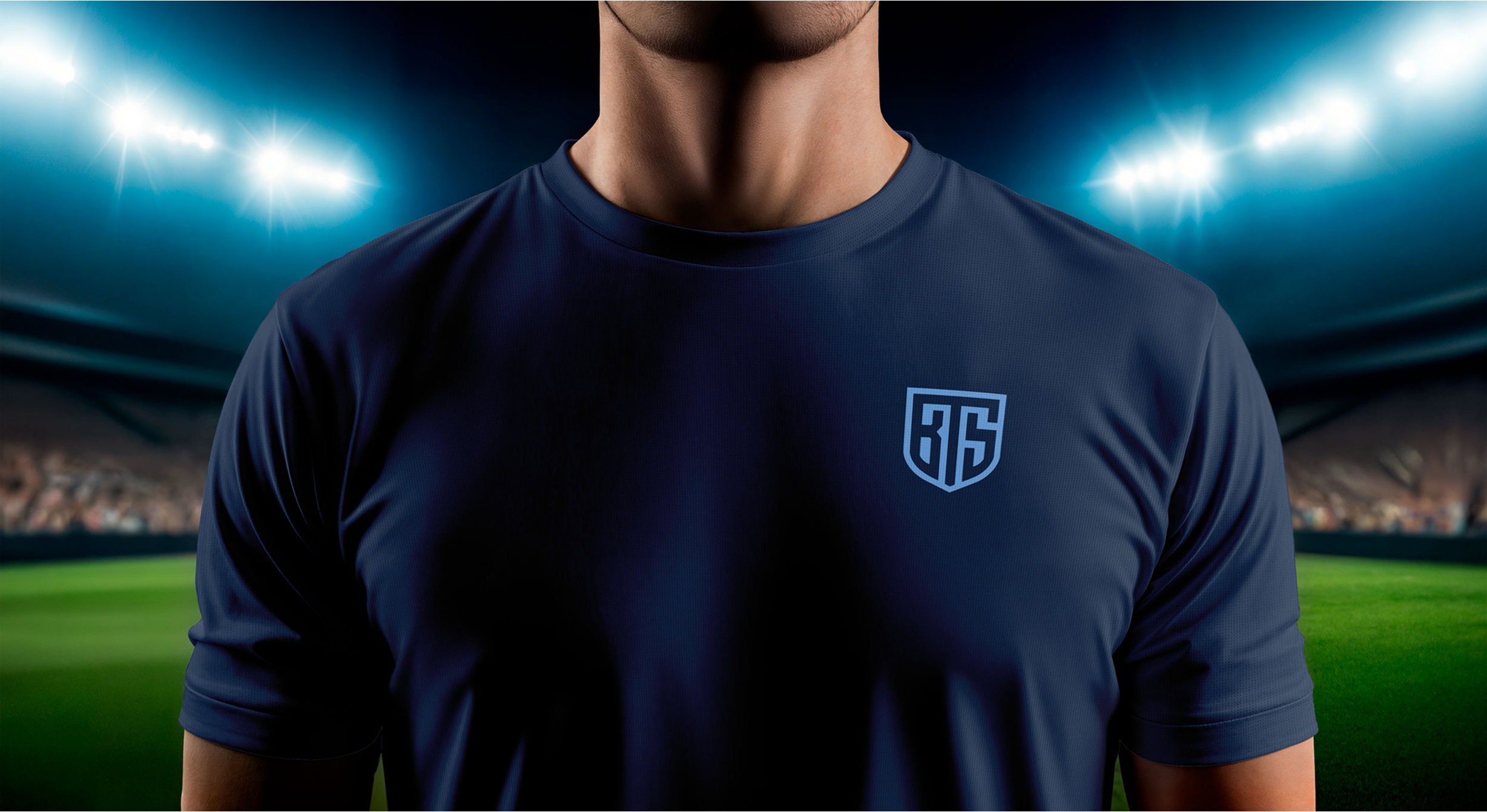 A person in a dark blue shirt with bright blue shield logo in a brightly lit stadium at night. The logo contains the letters "BTS." The atmosphere is intense and focused, with a blurry crowd in the background.