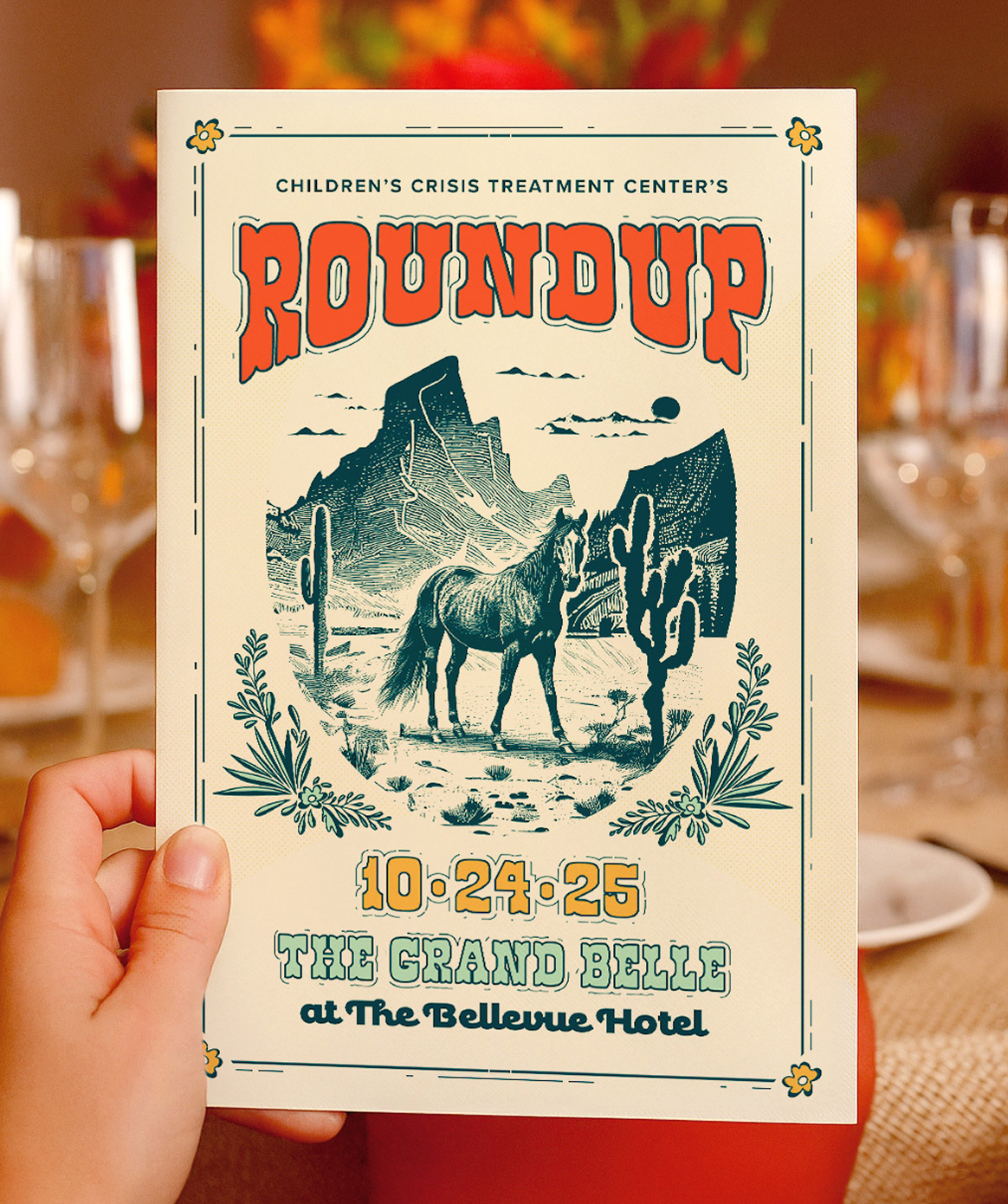 Roundup-Program Cover for CCTC's Roundup program book. It features "Roundup" in bold orange letters, a central illustration of a horse in a dessert setting, and event information below. The program is being held with a blurred table setting in the background.